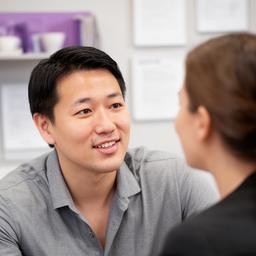 Portrait of Junrui Gutstadt speaking with a client in a tidy CPA office