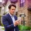 Property specialist outside a townhouse reviewing a secure message on a phone